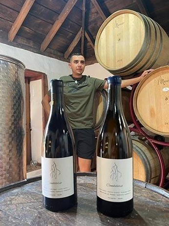 Michael Candelario all'interno della sua cantina con le bottiglie di vino.